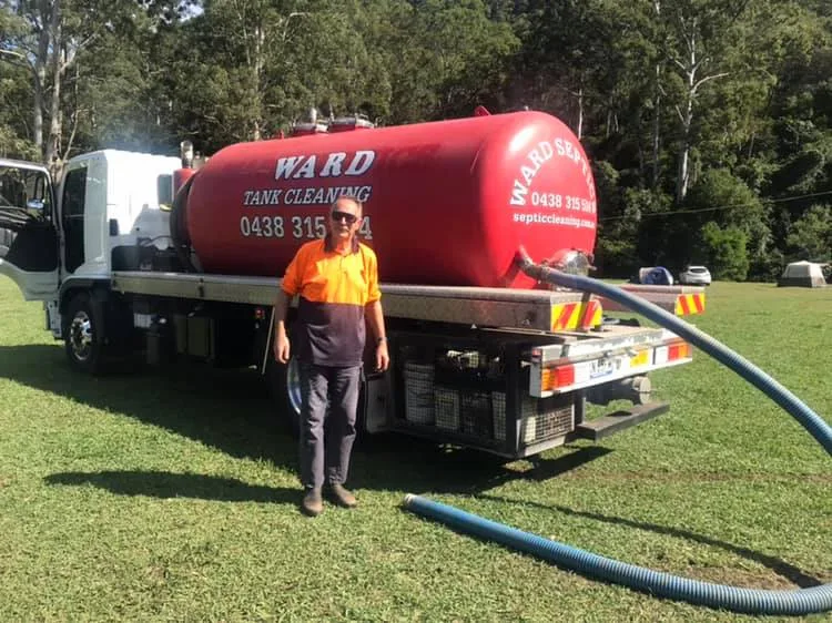 The operator standing beside the red Ward tank truck with the hose run out on a job