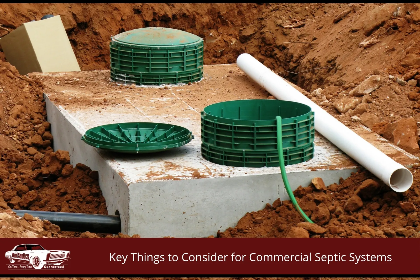 A large concrete commercial septic tank sits in an excavated dirt pit.