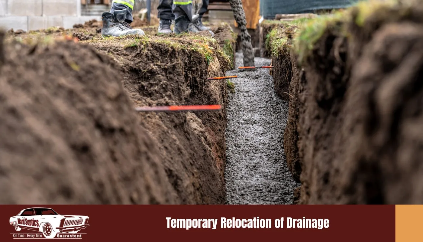 Wet concrete is poured into a narrow dirt trench at a construction site