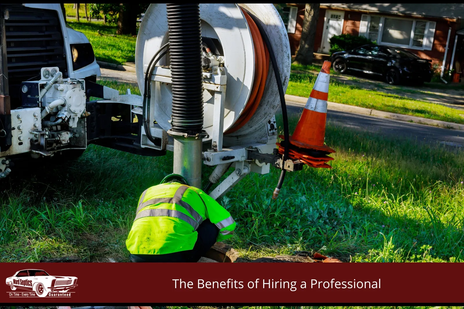 A municipal or utility worker in a high-visibility green jacket leaning over an open ground-level manhole next to a large vacuum truck with an integrated hose reel unit.