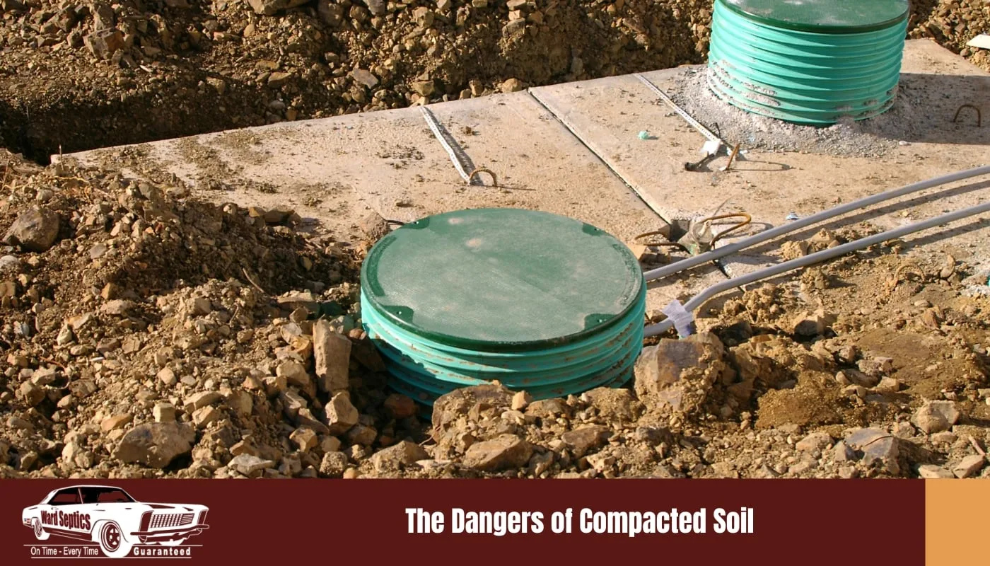 Two green corrugated plastic septic tank risers with lids installed on a concrete slab base surrounded by loose, rocky dirt.