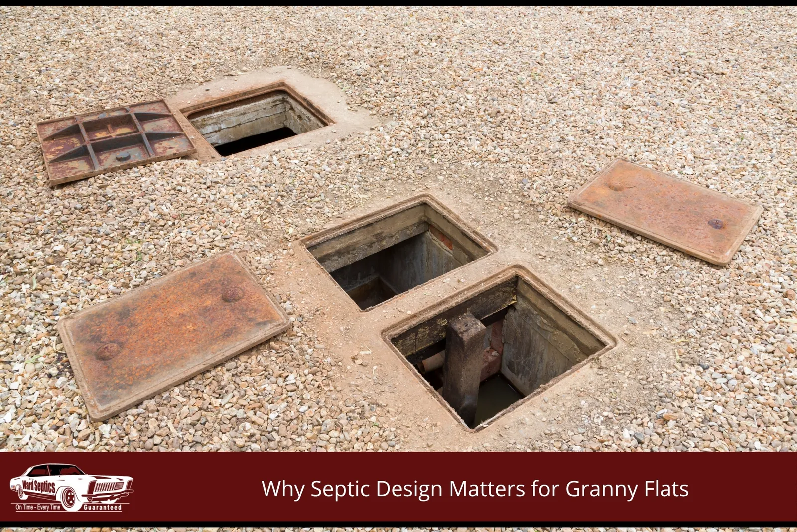 A three open, rectangular concrete access chambers set into a gravel area with their rusty metal lids set aside.
