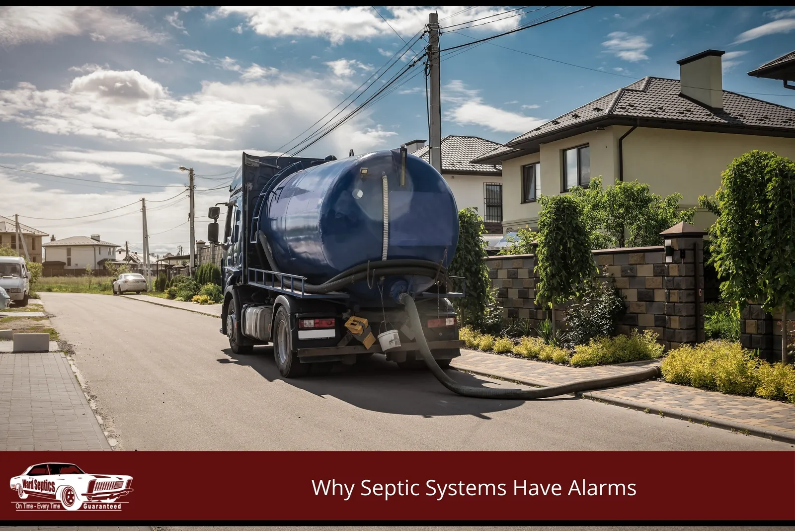 A large liquid waste tank parked on a residential street next to a house, with a suction hose running across the pavement onto the property.