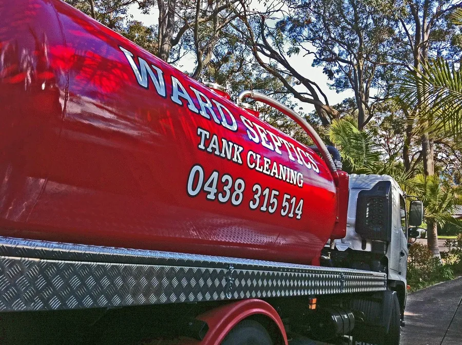 Close view of the red Ward Septics tank cleaning barrel under dappled tree light