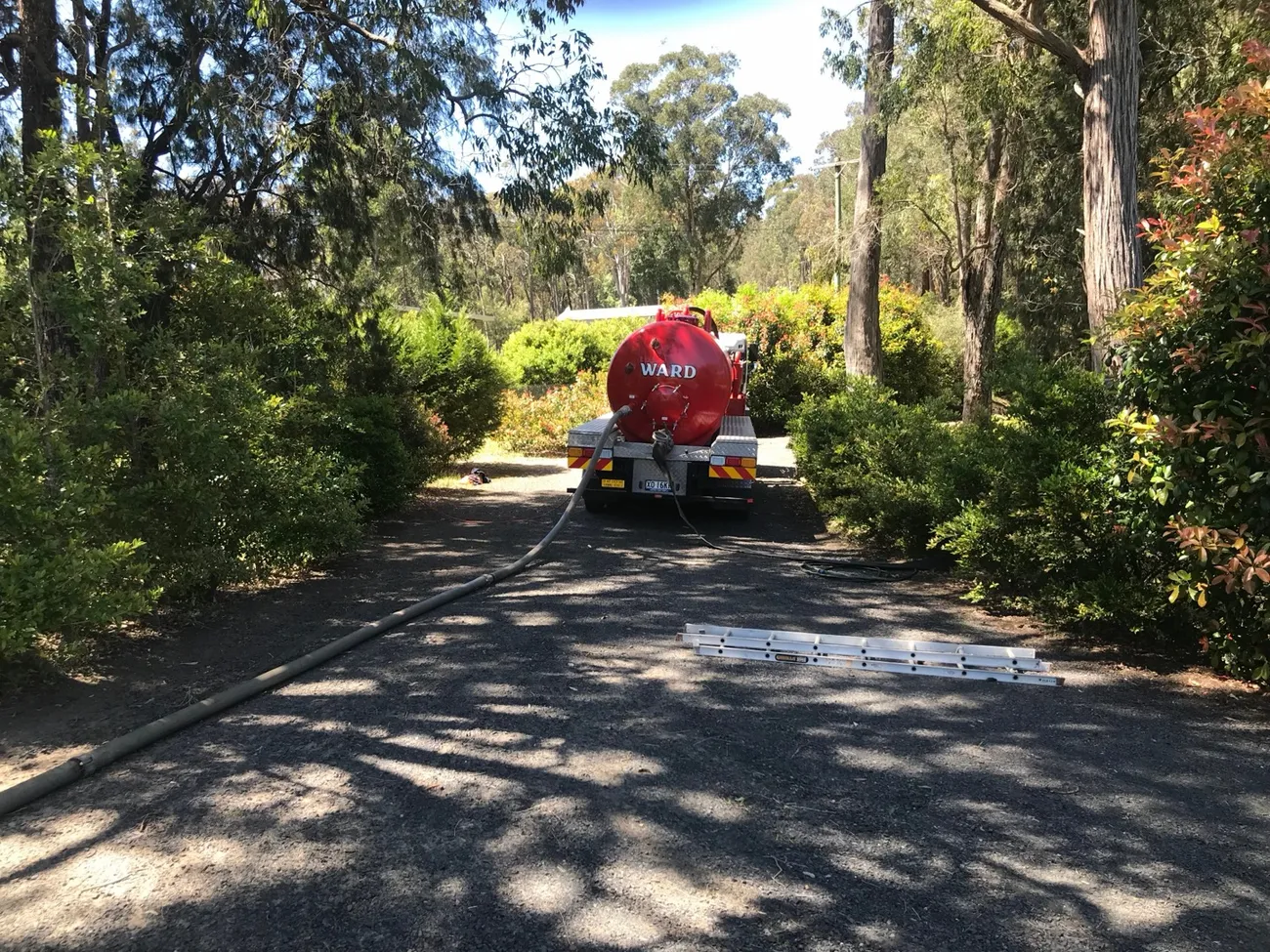 Pump-out hose making its way down a long tree-lined Central Coast driveway to the truck