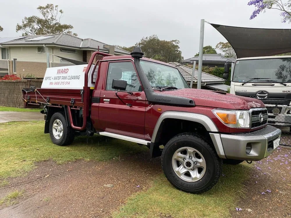The maroon Ward Septic and Water Tank Cleaning ute parked at a Lake Macquarie home, tank truck behind it