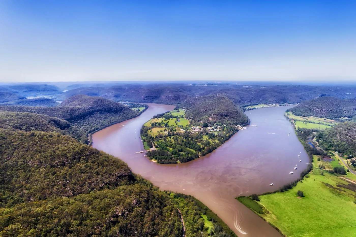 The Hawkesbury River winding around a green farmed bend at Gunderman under a blue sky