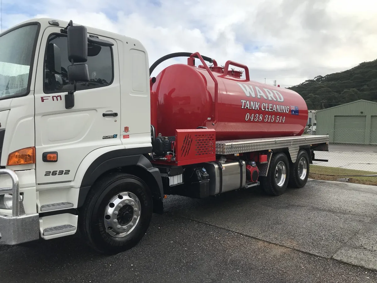 The red Ward Tank Cleaning vacuum tanker from behind, hoses racked and ready