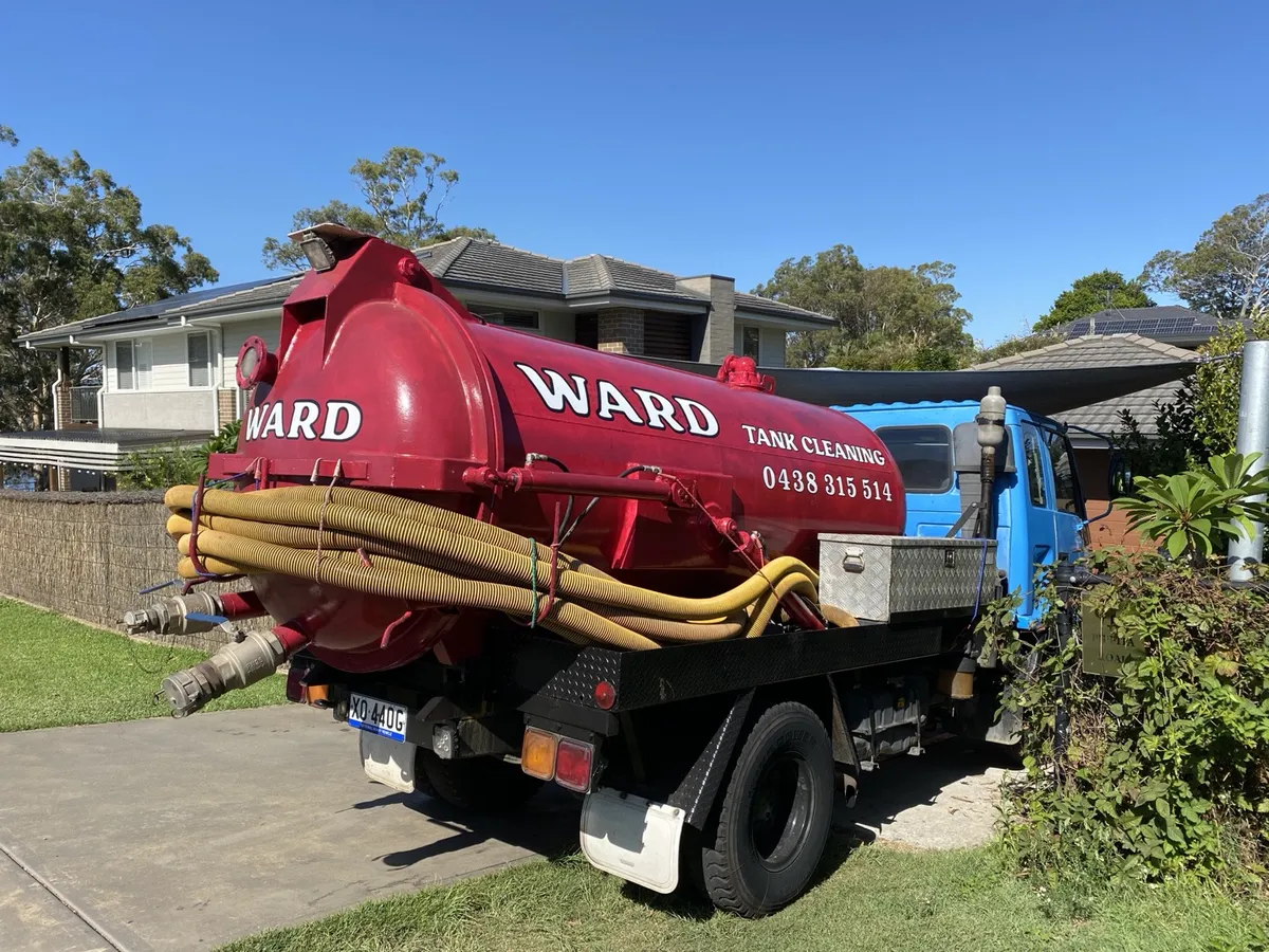 The old maroon WARD tank with white serif lettering, loaded on the blue truck in a suburban street